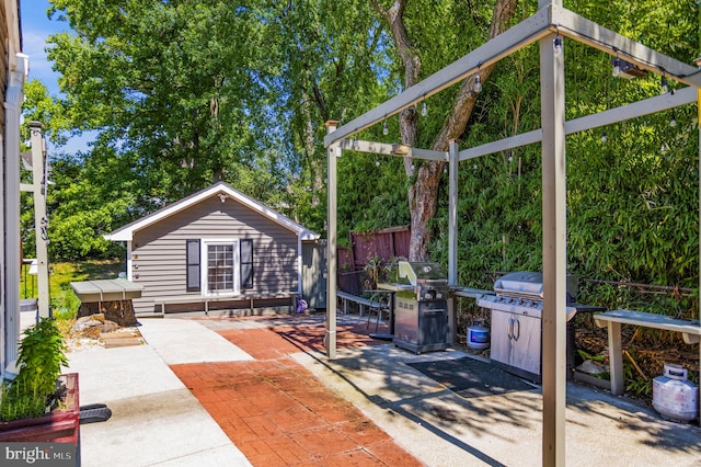 view of patio with an outbuilding, fence, and area for grilling