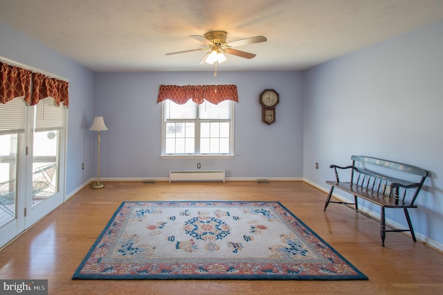 sitting room featuring baseboards, a ceiling fan, baseboard heating, and wood finished floors