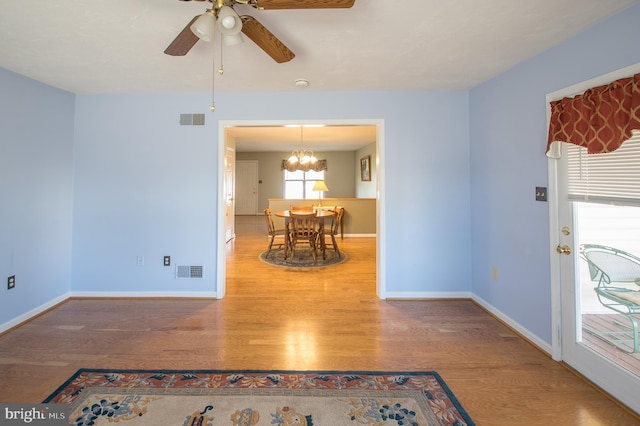 dining room with ceiling fan with notable chandelier, wood finished floors, visible vents, and baseboards