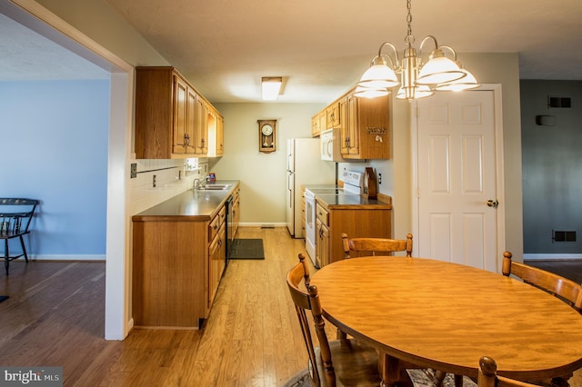 kitchen with white appliances, visible vents, baseboards, light wood-style floors, and brown cabinets