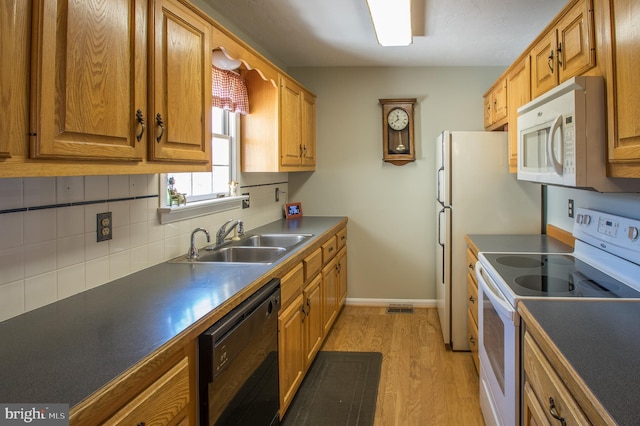 kitchen featuring light wood finished floors, tasteful backsplash, a sink, white appliances, and baseboards