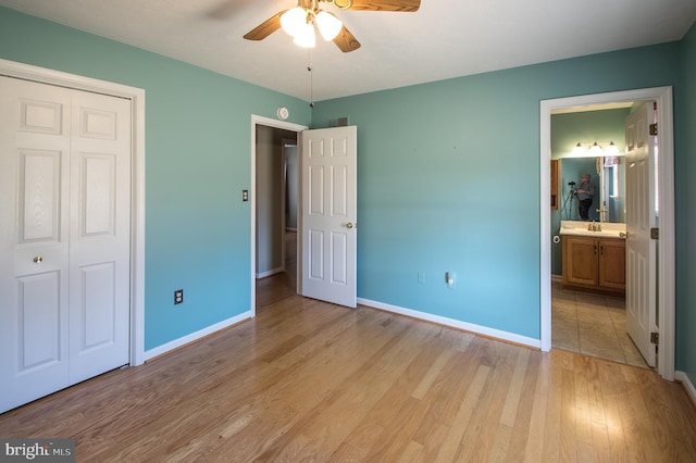 unfurnished bedroom with light wood finished floors, a closet, a sink, and baseboards