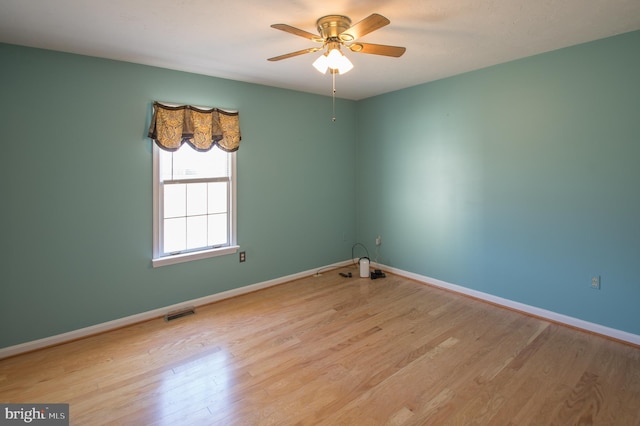 empty room with visible vents, baseboards, ceiling fan, and wood finished floors