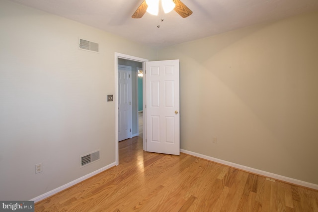 empty room featuring light wood-style floors, visible vents, ceiling fan, and baseboards