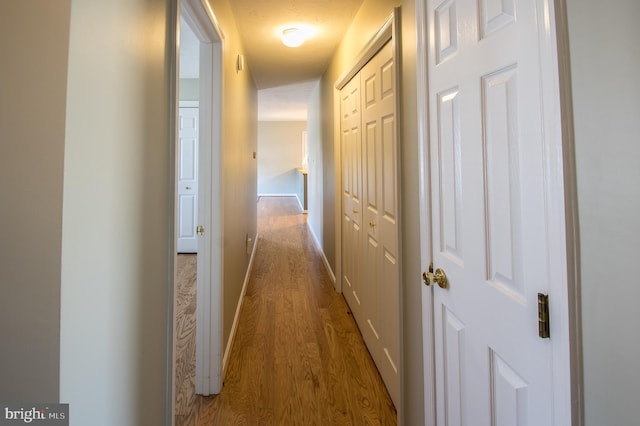 hallway with baseboards and wood finished floors