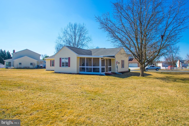 back of house featuring a sunroom and a lawn