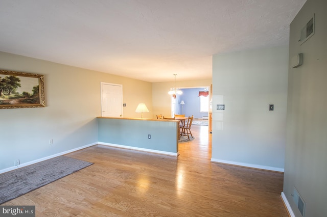 interior space featuring a notable chandelier, baseboards, visible vents, and wood finished floors