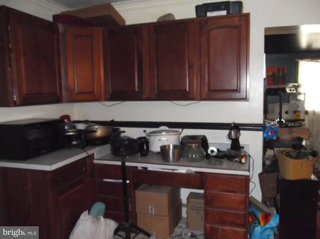 kitchen with light countertops, ornamental molding, and reddish brown cabinets