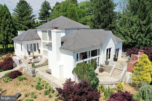 back of house featuring a shingled roof, fence, french doors, stucco siding, and a chimney