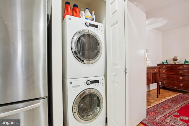 laundry area featuring crown molding, stacked washer / dryer, and wood finished floors