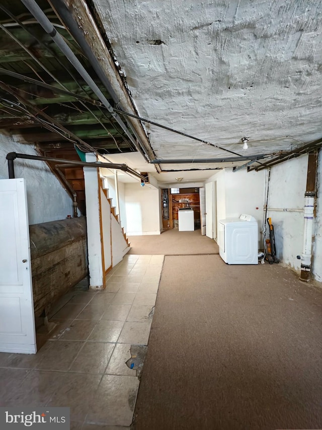 unfinished below grade area featuring stairs and washer / clothes dryer