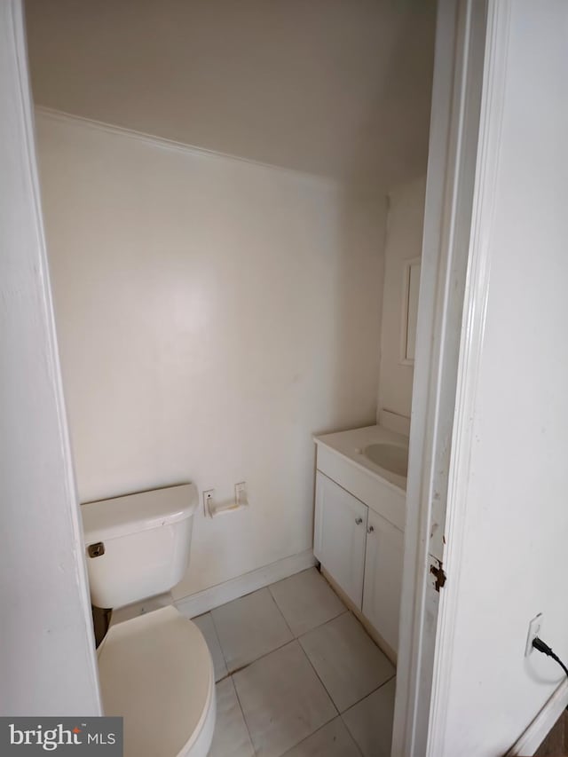 half bath featuring baseboards, vanity, toilet, and tile patterned floors