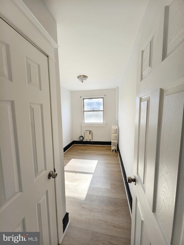 hall with radiator, light wood-style floors, and baseboards