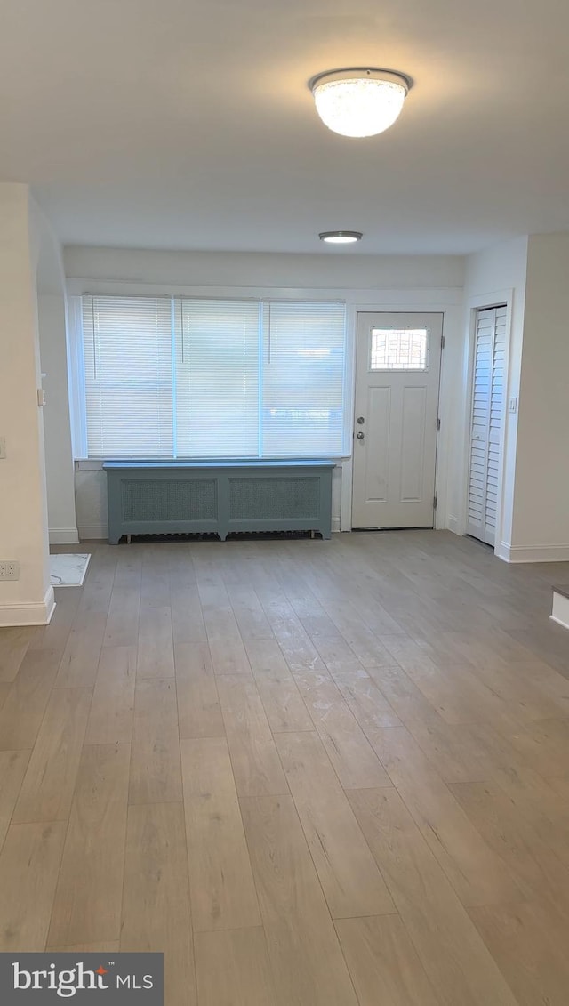 entryway with baseboards, wood finished floors, and radiator