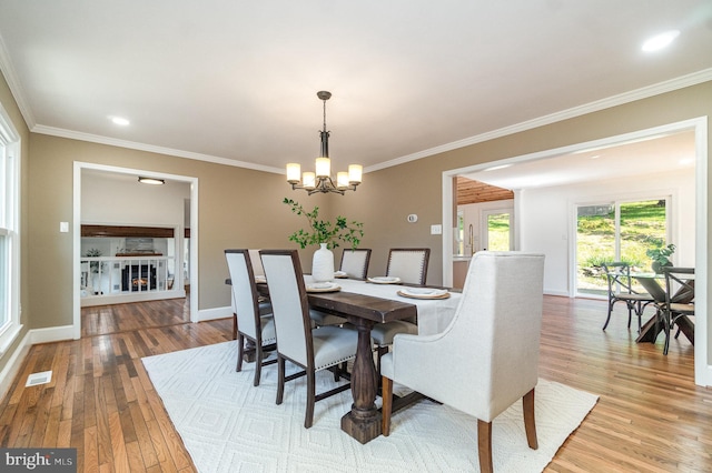 dining room featuring crown molding, a notable chandelier, visible vents, wood finished floors, and baseboards