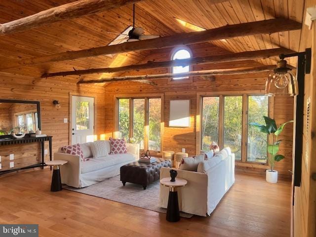 living area with lofted ceiling with beams, wooden ceiling, wooden walls, wood finished floors, and a ceiling fan