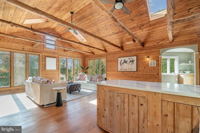 interior space with lofted ceiling with skylight, wood walls, ceiling fan, light wood-type flooring, and wooden ceiling