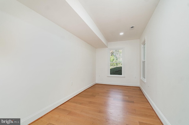 empty room featuring light wood finished floors, visible vents, and baseboards