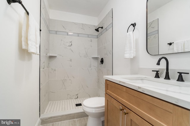 full bathroom with a tile shower, vanity, and toilet