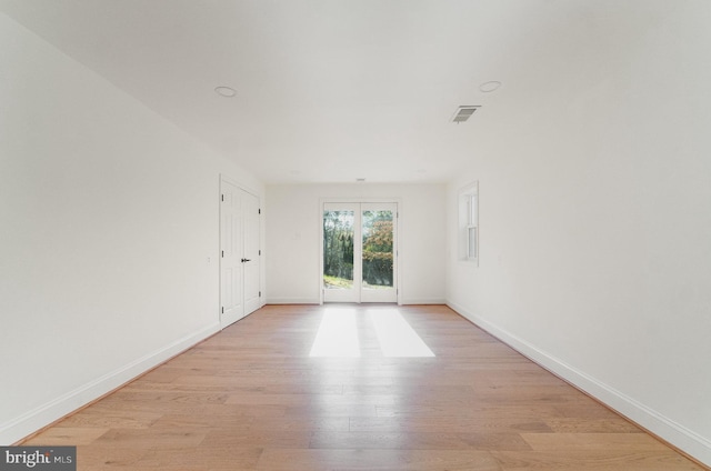 spare room with light wood finished floors, visible vents, and baseboards