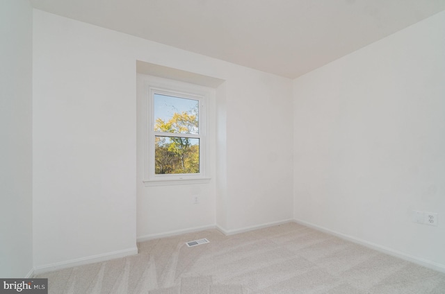 unfurnished room featuring baseboards, visible vents, and light colored carpet