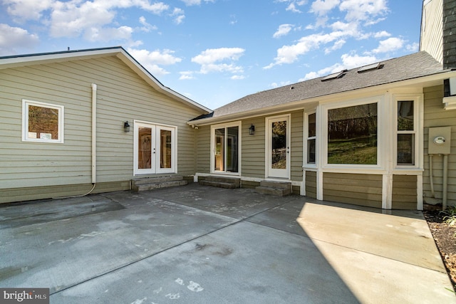 rear view of property featuring entry steps, a patio area, a shingled roof, and french doors