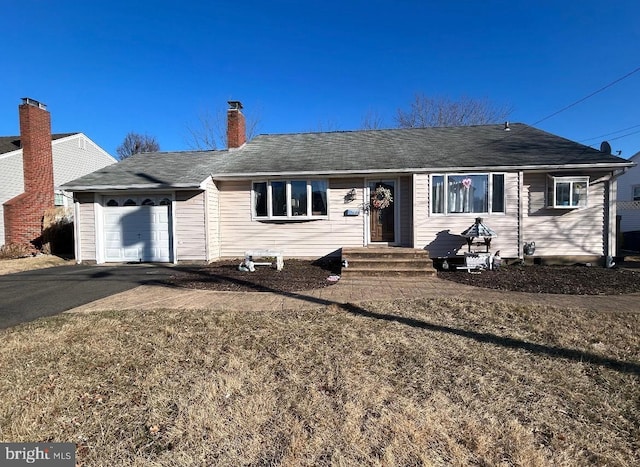 single story home featuring a garage, a chimney, and aphalt driveway