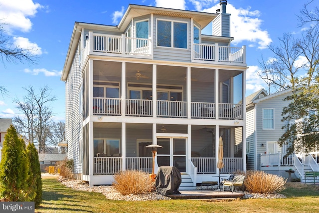 back of property with a patio, a balcony, a sunroom, and a chimney