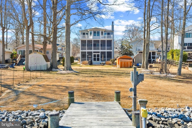 rear view of property with an outdoor structure, fence, a sunroom, a yard, and a shed