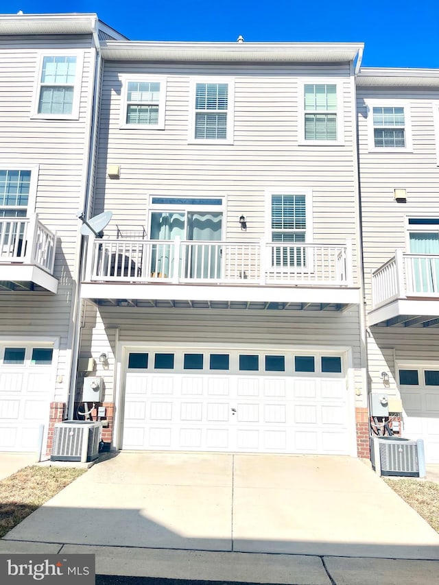 rear view of house featuring an attached garage, driveway, and central AC unit