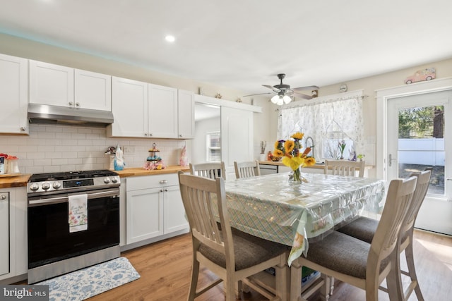 kitchen with decorative backsplash, wood counters, stainless steel range with gas stovetop, and under cabinet range hood