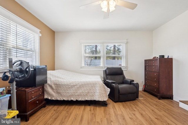 bedroom with light wood-style flooring, multiple windows, baseboards, and a ceiling fan