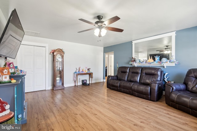 living area with light wood finished floors, baseboards, visible vents, and a ceiling fan