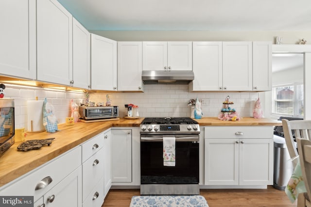 kitchen featuring under cabinet range hood, wood counters, white cabinets, and gas stove