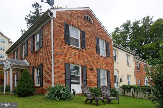 back of property with brick siding and a yard