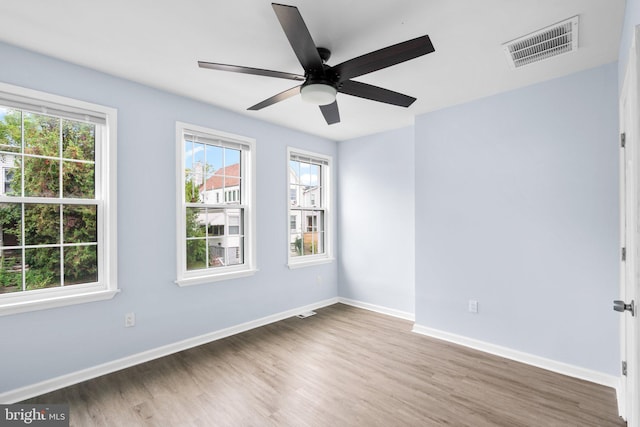 spare room with visible vents, ceiling fan, baseboards, and wood finished floors