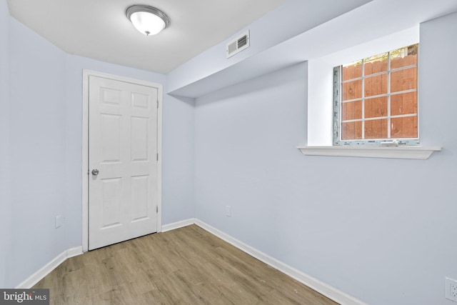 empty room with wood finished floors, visible vents, and baseboards