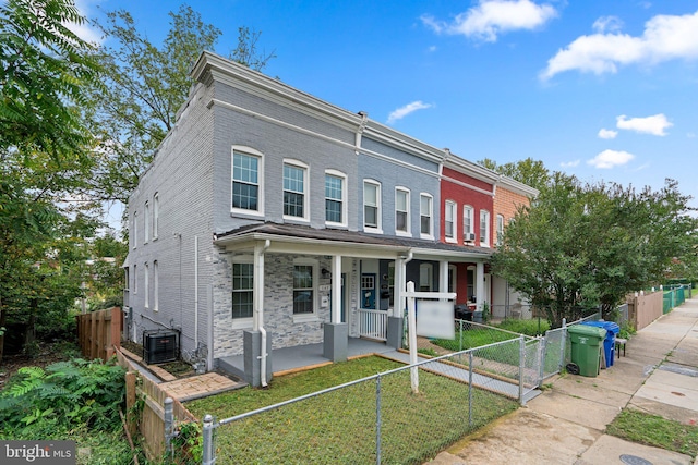 townhome / multi-family property featuring a porch, a fenced front yard, brick siding, stone siding, and a gate