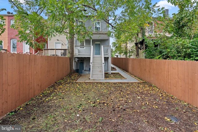 back of property with a fenced backyard and stairway