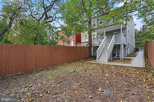 rear view of house with a fenced backyard and stairway