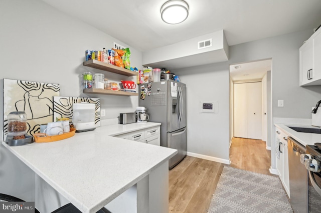 kitchen featuring light wood-style flooring, a sink, visible vents, light countertops, and stainless steel fridge with ice dispenser