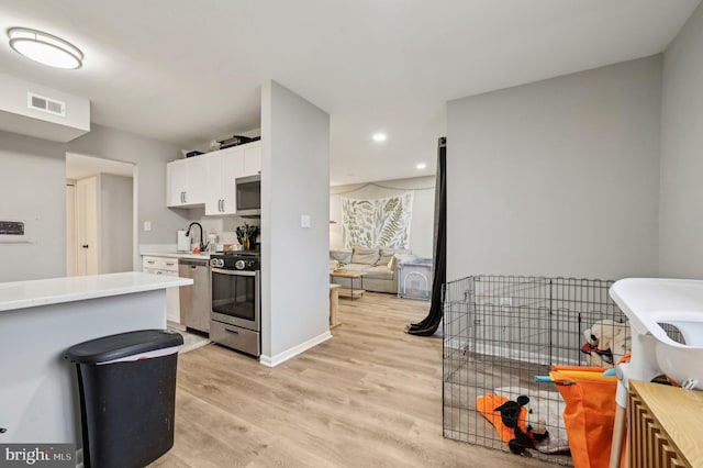 kitchen with light countertops, visible vents, light wood-style flooring, appliances with stainless steel finishes, and white cabinets