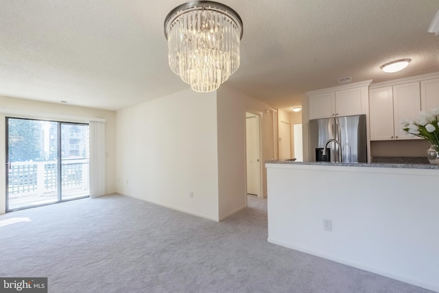 kitchen featuring stainless steel refrigerator with ice dispenser, an inviting chandelier, white cabinetry, light carpet, and a textured ceiling