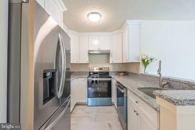 kitchen with white cabinets, stainless steel appliances, a textured ceiling, under cabinet range hood, and a sink