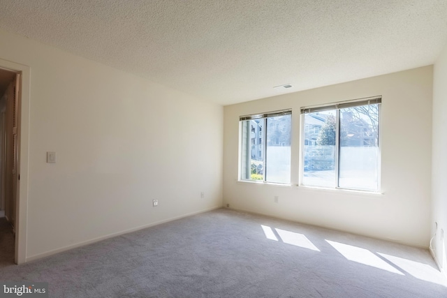 carpeted empty room with a textured ceiling