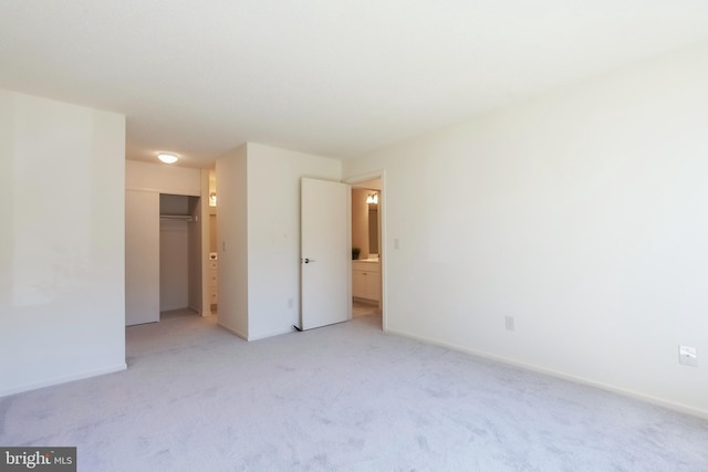 spare room featuring light carpet and baseboards