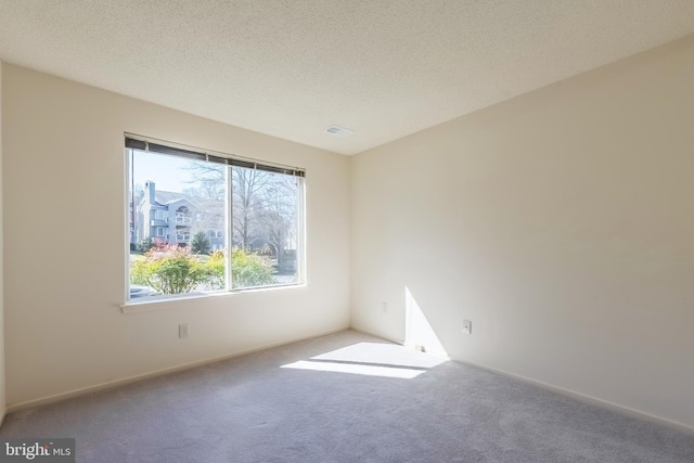 carpeted empty room featuring visible vents and a textured ceiling