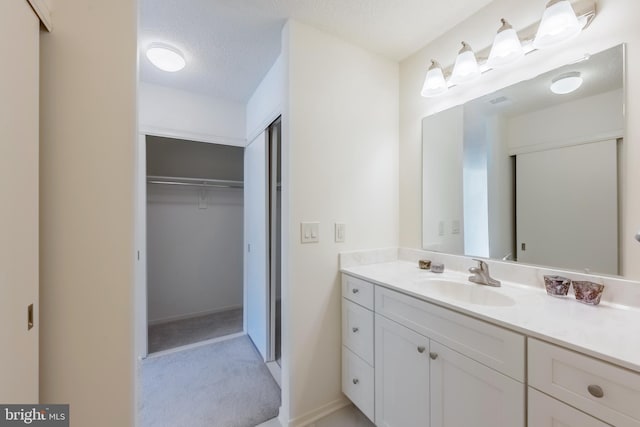 bathroom with a textured ceiling, a spacious closet, and vanity