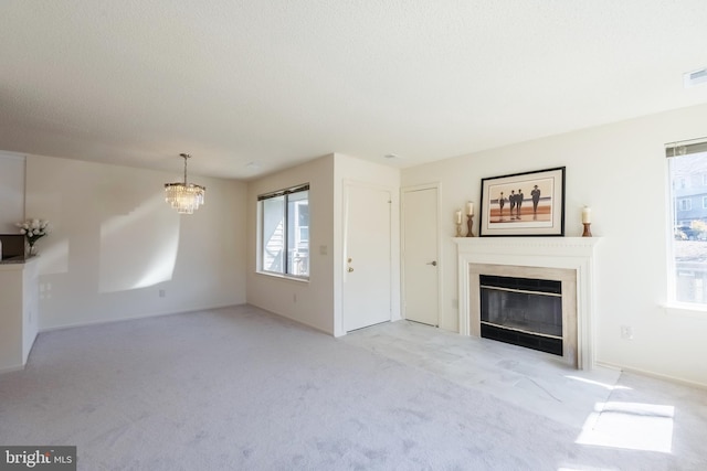 unfurnished living room featuring a notable chandelier, visible vents, a fireplace with flush hearth, light carpet, and a textured ceiling