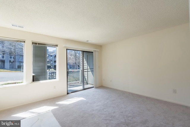 carpeted spare room with visible vents, a textured ceiling, and baseboards